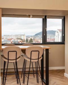 a room with a table with three chairs and a large window at Distinct Ultracentral Apartment in Bistriţa