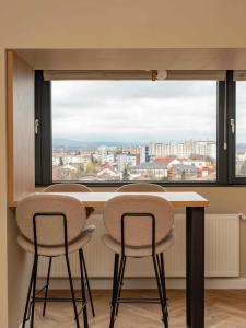 a table with three chairs in front of a large window at Distinct Ultracentral Apartment in Bistriţa