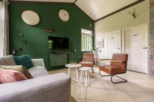 a living room with a couch and chairs and a clock at Bungalow de Mees in Schoonloo