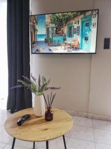 a tv hanging on a wall with a vase on a table at Nord Guesthouse in Neos Pirgos