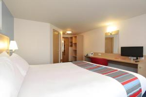 a hotel room with a large white bed and a desk at Travelodge Egham in Egham