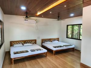 two beds in a room with wooden floors and windows at Awas Beach Stays in Avas