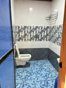 a bathroom with a toilet and a blue floor at Awas Beach Stays in Avas