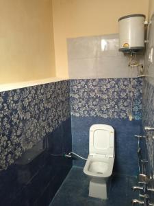 a bathroom with a toilet and a blue tiled wall at Divine homestay in Kukri Ser