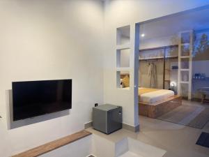 a bedroom with a bed and a flat screen tv at Aluna Villa Kintamani - Private villa & Hot spring pool in Kubupenlokan
