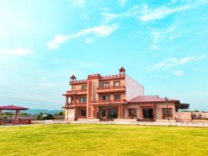 a large building with a grass field in front of it at Infinity Hotel & Resort, Chikani , Alwar in Alwar