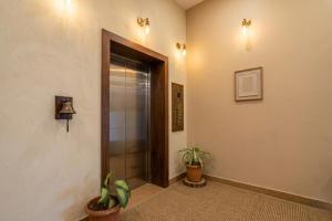 a hallway with a door and two potted plants at Hotel Shumo Grand Khammam in Khammam