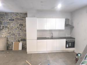 a kitchen with white cabinets and a stone wall at appartement luna 1 in Dinant