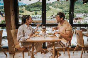 a man and woman sitting at a table eating food at Landhaus Albert Murr inkl Premium Sommerkarte in Sankt Anton am Arlberg