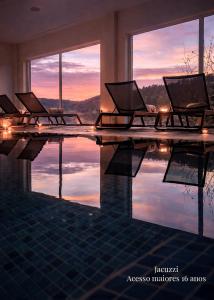 a swimming pool with chairs and a reflection in the water at Hotel Rural Quinta da Conchada in Aguieira