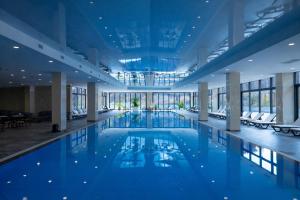 a large swimming pool in a building with windows at Eighty Eight Deluxe Hotel & Spa in Tsaghkadzor