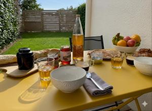 a table with bowls and glasses and a bottle of wine at La Pause de Mérimée - Jardin - Parking in Vannes