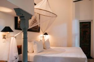 a bedroom with a white bed with a netussed canopy at Boutique 87 in Bentota