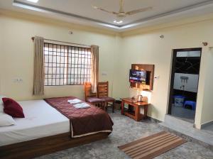a bedroom with a bed and a desk and a television at RK Comforts in Belūr