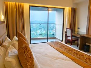 a bedroom with a bed and a desk and a large window at Hotel Grand Pacific in Cox's Bazar