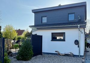 a white and black house with a black door at Inselbutze Fehmarn in Fehmarn