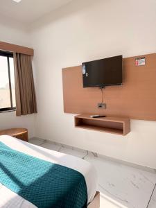 a room with a bed and a flat screen tv on a wall at HOTEL ROSE PRIMe in Anand