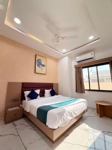 a bedroom with a large bed with blue pillows at HOTEL ROSE PRIMe in Anand