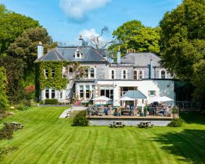 a large house with a yard with tables and chairs at Penmorvah Manor Hotel in Falmouth