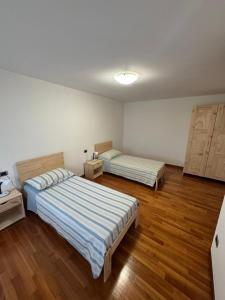two beds in a room with wooden floors at Alloggio ai Campanari in Conco
