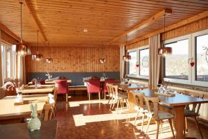 a dining room with tables and chairs and windows at Pension KaraMia in Fichtelberg
