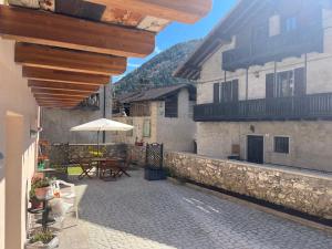 a patio with a table and an umbrella and two buildings at Ca' Bertera in Ledro