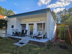 a small white house with chairs and a swing at Haus am Waldesrand in Wustrow