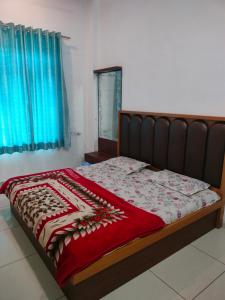 a bed with a red blanket on top of it at Hotel Keshav in Rīngas +2 photos