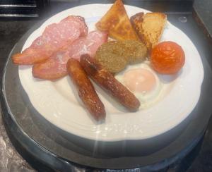 a plate of breakfast food with sausage and eggs at Dacara Bed & Breakfast in Newcastle