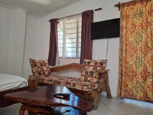 a room with a bed and a chair and a table at Susans cottages diani beach in Ukunda