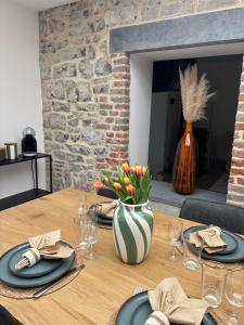 a wooden table with plates and glasses and a vase with flowers at Appartement chez pépite in Namur