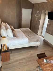 a bedroom with a bed and a table with a lamp at Hôtel et SPA des sources du gros noyer in Malaucène