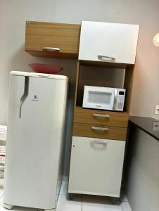 a small kitchen with a refrigerator and a microwave at Dunas residence casa 04 in Santo Amaro