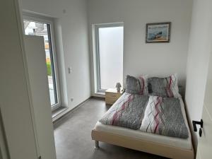 a white bedroom with a bed and two windows at Thiels Mansion in Sankt Sebastian
