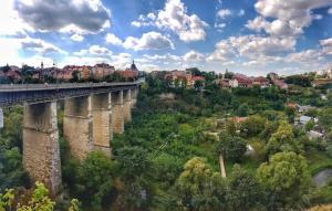 a train traveling over a bridge over a city at Апартаменти над каньйоном in Kamianets-Podilskyi