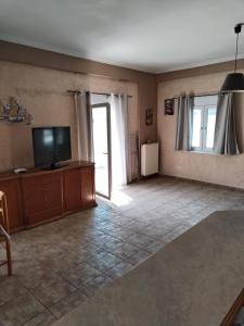 a living room with a flat screen tv and a large window at Takis House in Gavrio