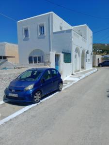 a blue car parked in front of a white house at Takis House in Gavrio