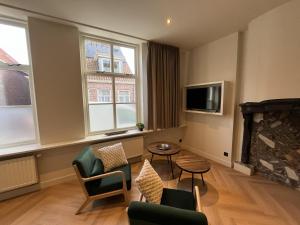 a living room with a fireplace and chairs and a tv at Appartementen het Centrum in Domburg