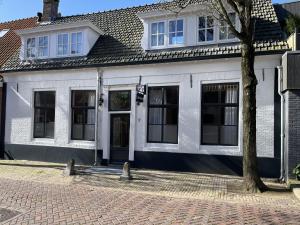 a white building with a tree in front of it at Appartementen het Centrum in Domburg