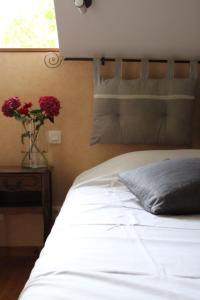 a white bed with a vase of red flowers on a table at La Table de Gabin in Saint-Léonard