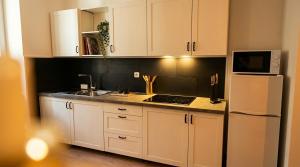 a kitchen with white cabinets and a white refrigerator at Appartement Ubac - Chic & Douillet in Saint-Gaudens