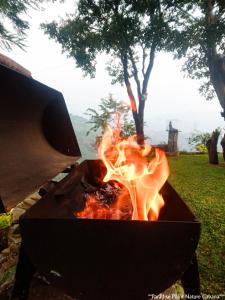 a grill with a fire in it in a field at Paradise Point Nature Cabana Kandy in Kande