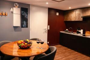 a wooden table with a bowl of fruit and wine glasses at Suite Phoenix - Maison Cosy avec Terrasse & Cinéma Privé in Angoulême