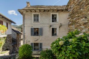 an old stone house with windows and a hedge at Bnbook Ca Du Val in Falmenta
