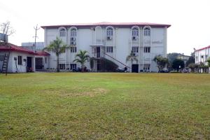 a large white building with a large grass field at Hotel Royal Maithan International in Garphalbāri