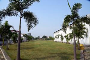 a park with palm trees in front of a building at Hotel Royal Maithan International in Garphalbāri