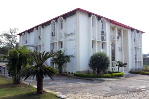 a large white building with palm trees in front of it at Hotel Royal Maithan International in Garphalbāri