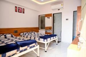 a room with two beds in a room at Laxman AC Lodge Jejuri - by Martandbhairav hospitality LLP in Jejūri +1 photo