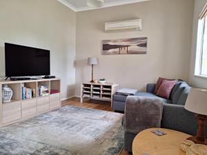 a living room with a couch and a tv at Abbivale Farm Cottage in Harewood
