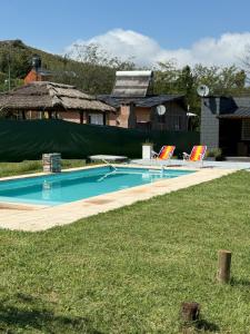 a swimming pool with two lawn chairs in front of a house at Potrero Village Suites Refugios Serranos in Potrero de Garay